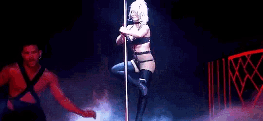 a woman is dancing on a pole on a stage in a dark room .