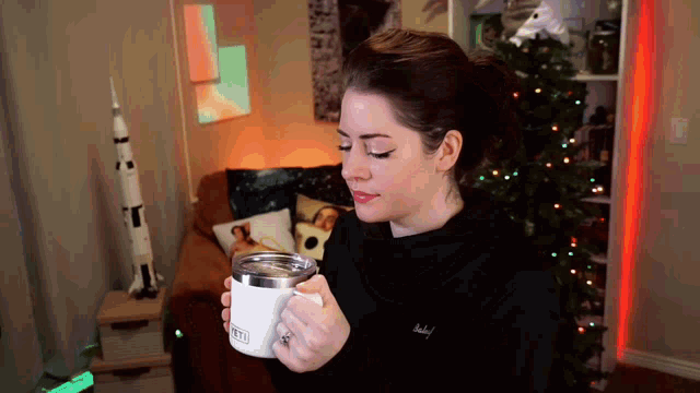 a woman is holding a white mug that says yeti