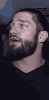 a man with a beard and long hair is sitting in a car .