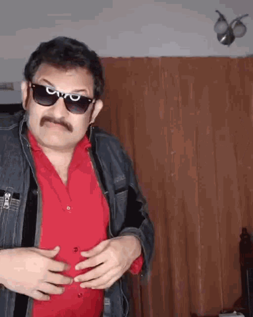 a man wearing sunglasses and a red shirt is holding his belly