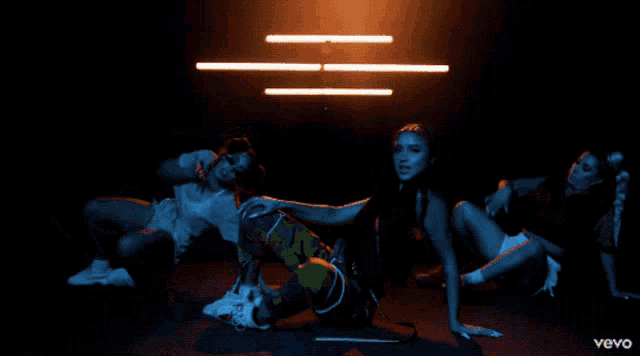 three women are dancing in a dark room with the word vevo on the bottom left