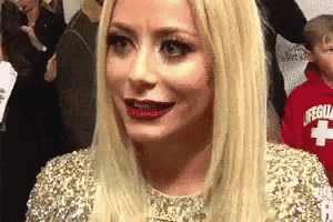 a woman with long blonde hair is wearing a gold dress and a red lifeguard sweatshirt .