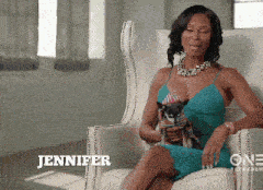 a woman in a blue dress is sitting in a chair holding a small dog with the name jennifer on the bottom
