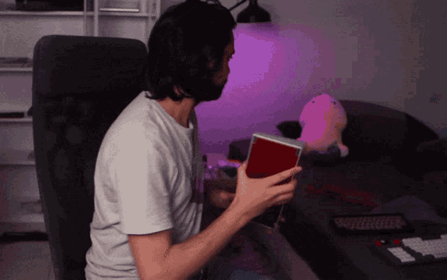 a man sits in a chair holding a red box that says ' nintendo ' on it