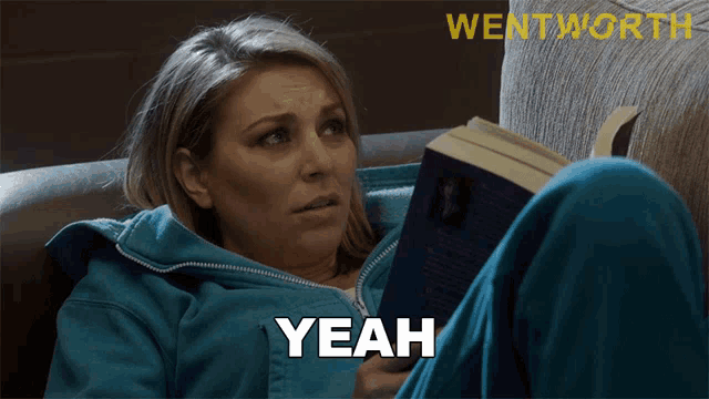 a woman sitting on a couch reading a book with the word yeah written on her shirt
