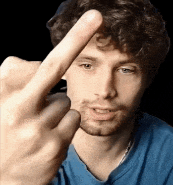 a man in a blue shirt is giving the middle finger to the camera