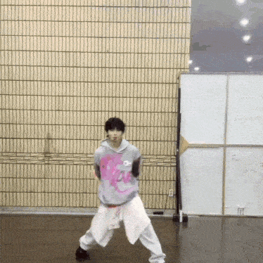 a young man is standing in front of a brick wall while dancing .
