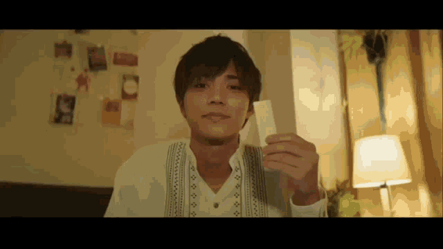 a man in a white shirt is holding a piece of paper in his hand .