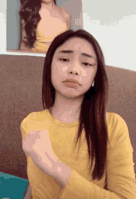 a woman in a yellow shirt is making a face