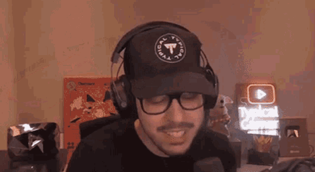 a man wearing glasses and headphones flexes his muscles in front of a youtube sign