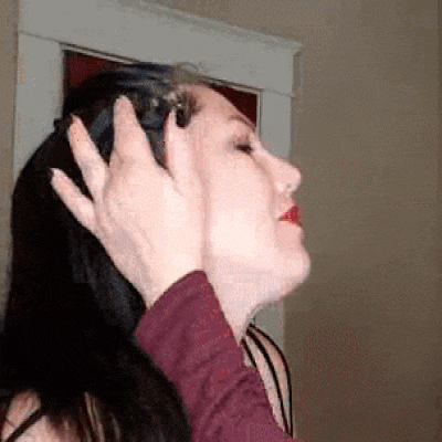 a woman with long black hair is being touched by another woman 's hand .