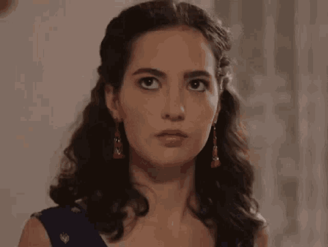 a close up of a woman wearing earrings and a blue dress