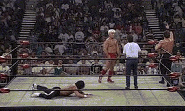 two men are wrestling in a ring with a referee in the background