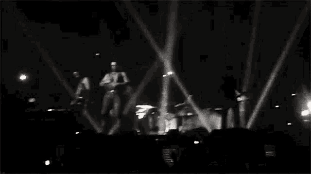 a black and white photo of a group of people dancing on a stage at a concert .
