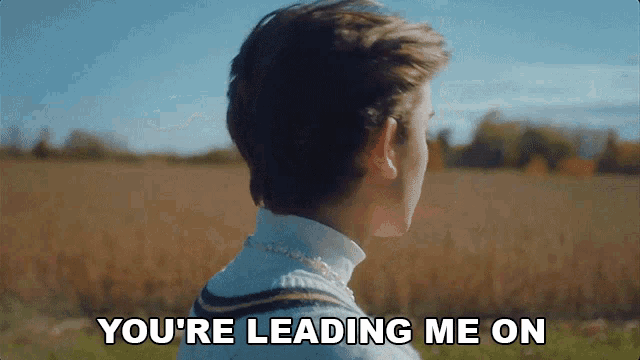 a man is standing in a field with the words " you 're leading me on " behind him