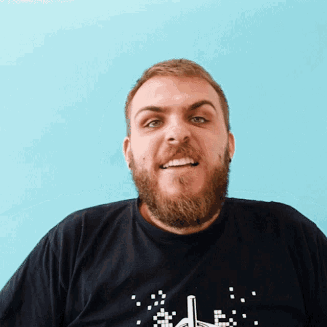 a man with a beard is wearing a black t-shirt with a pixelated rocket on it
