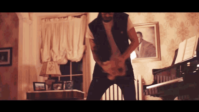 a man playing a guitar in a living room with a piano