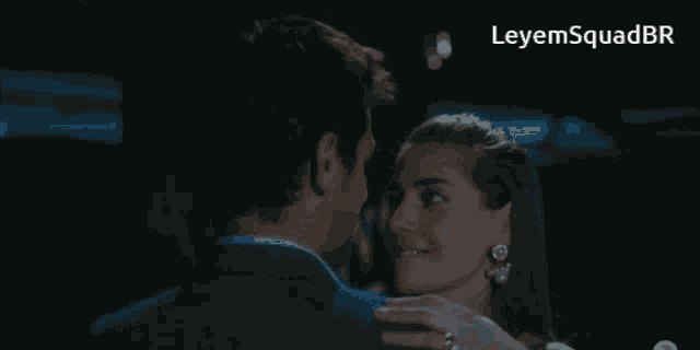a man and a woman are kissing in a dark room with the words leyemsquadbr on the bottom