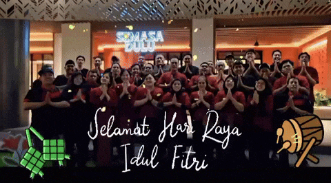 a group of people standing in front of a sign that says selamat hari raya idul fitri