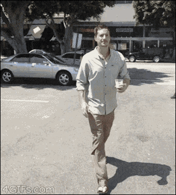 a man walking down a street with a cup in his hand