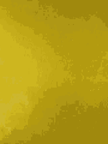a close up of a yellow wall with a few white spots on it