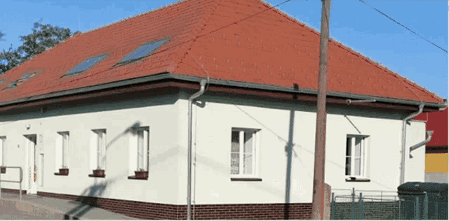 a white house with a red tiled roof and a few windows