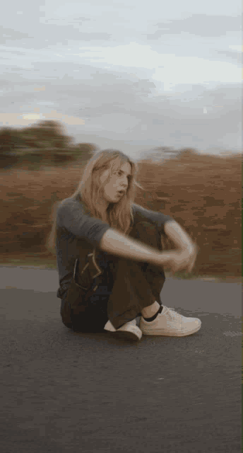 a blurry picture of a woman sitting on the side of a road
