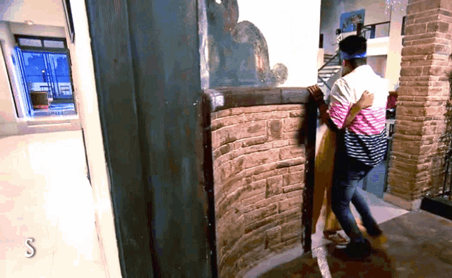 a man and woman hugging in front of a brick wall