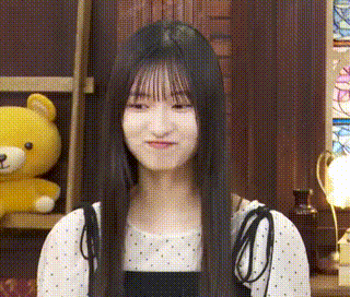 a girl with long black hair is standing in front of a teddy bear .