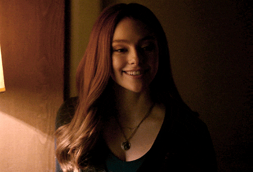 a woman wearing a black shirt and a necklace smiles