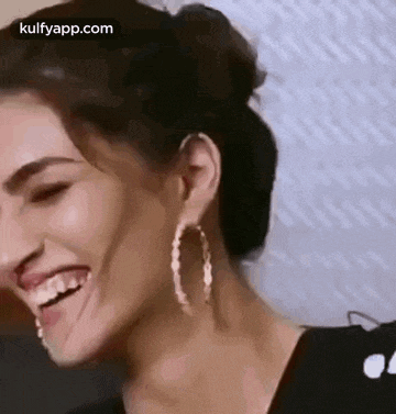 a woman wearing hoop earrings is making a funny face with her tongue out .