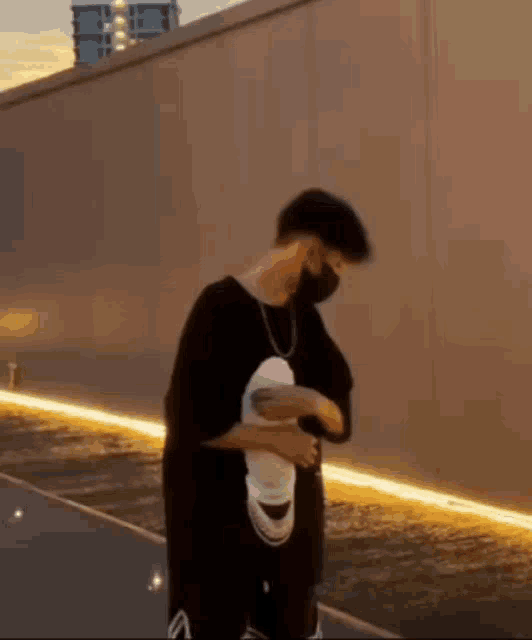 a man wearing a mask and a t-shirt is standing in front of a wall .