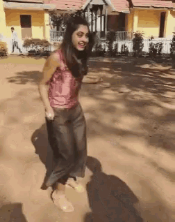 a woman is dancing in the dirt in front of a building