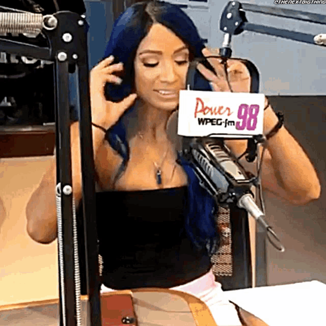 a woman with blue hair is wearing headphones and holding a power 98 sign