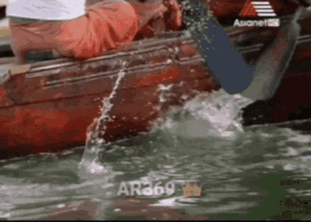 a person in a red boat is splashing in the water with the number ar369 on the bottom
