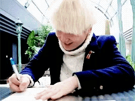 a man with white hair is writing on a piece of paper