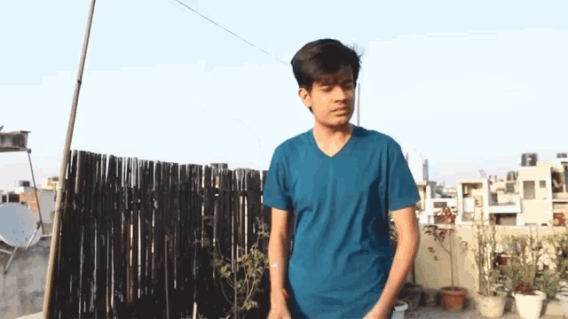a young man in a blue shirt is standing on a rooftop