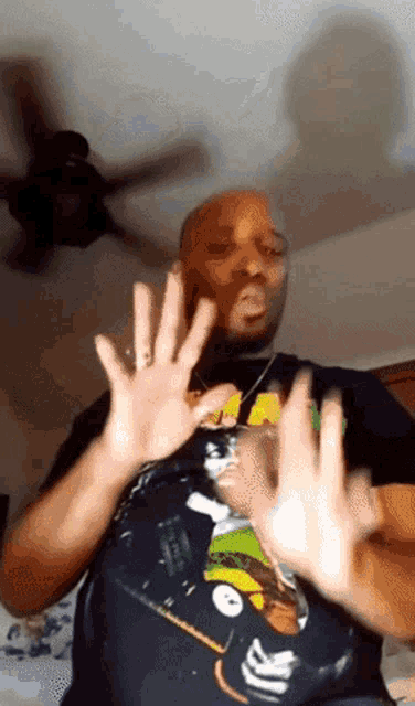 a man wearing a john deere shirt is making a stop sign with his hands