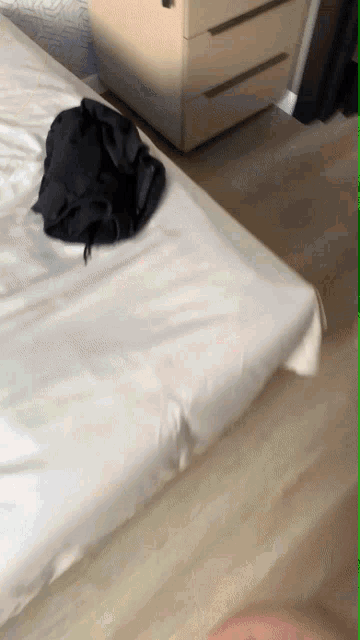 a bed with white sheets and a black jacket on it