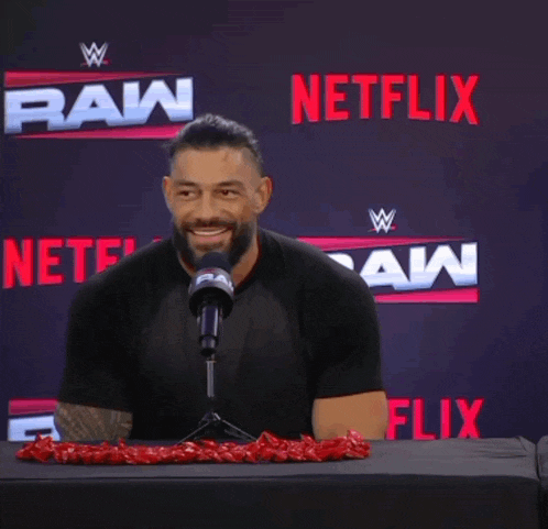 a man sitting in front of a microphone with netflix in the background