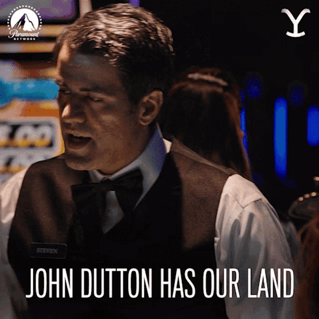 a man with a name tag that says steven stands in front of a sign that says john dutton has our land