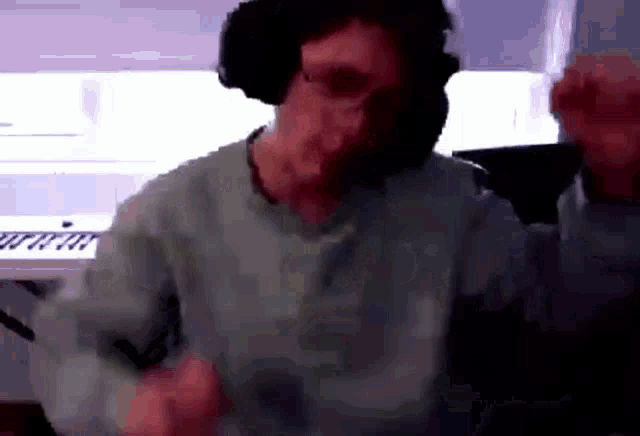 a man wearing headphones is dancing in front of a keyboard in a room .