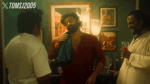 a man with a towel around his neck talks to two other men with xtomsj2005 written above them