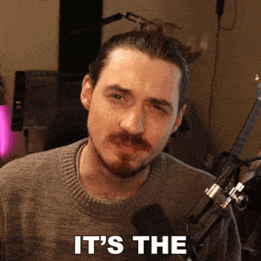 a man in front of a microphone with the words " it 's the " on his face