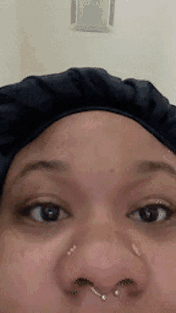 a close up of a woman 's face with a black cap on