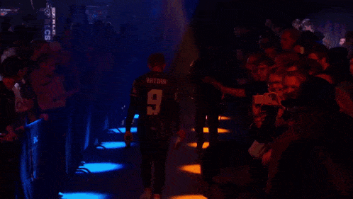 a man in a black shirt with the number 11 on it stands in front of a crowd