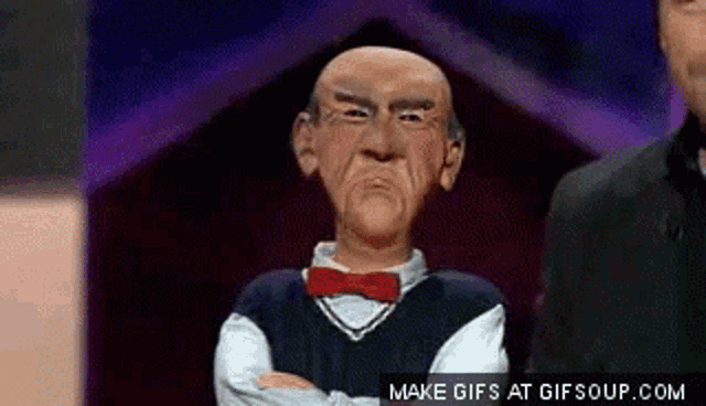 a puppet with a red bow tie is standing with his arms crossed ..