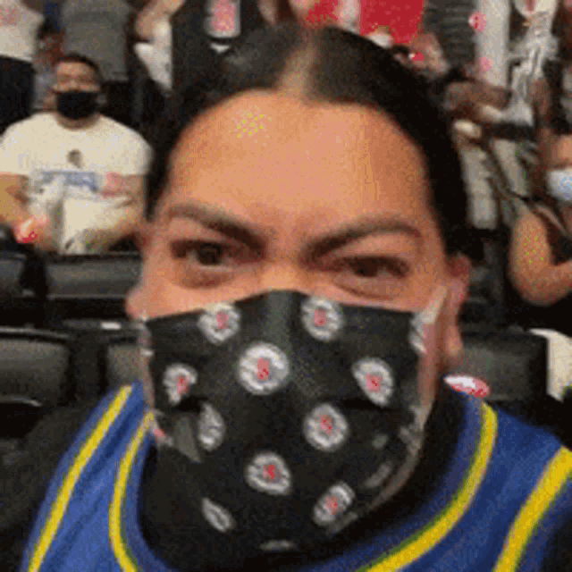 a man wearing a face mask is sitting in a crowd of people