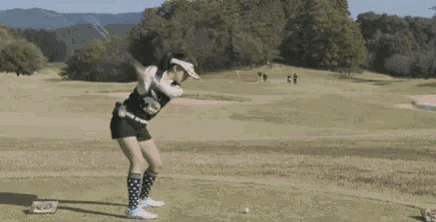 a woman wearing a ponytail and a visor is standing on a golf course