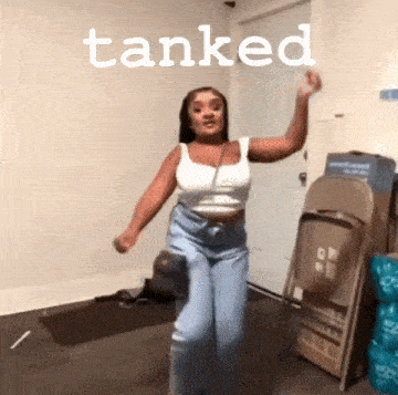 a woman in a white tank top and blue jeans is dancing in a room with the word tanked above her .